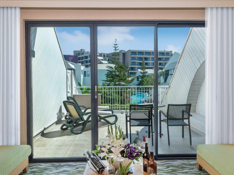 Balcon avec table, chaises et transat avec vue sur des bâtiments modernes.
