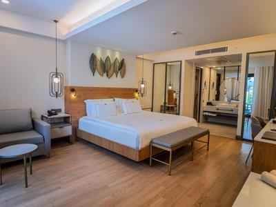 Camera d'hotel moderna con letto grande, area salotto e parete a specchio.