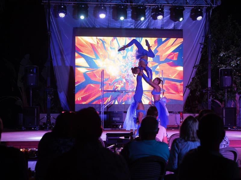 Artista danza davanti a uno schermo LED colorato e luminoso sul palco di fronte al pubblico.