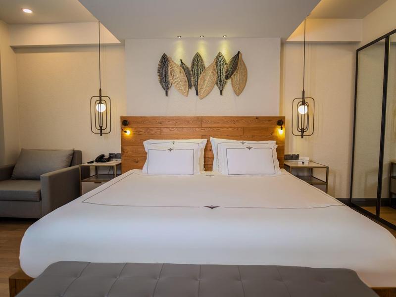 Camera d'hotel moderna con un grande letto matrimoniale, divano e decorazione murale elegante.