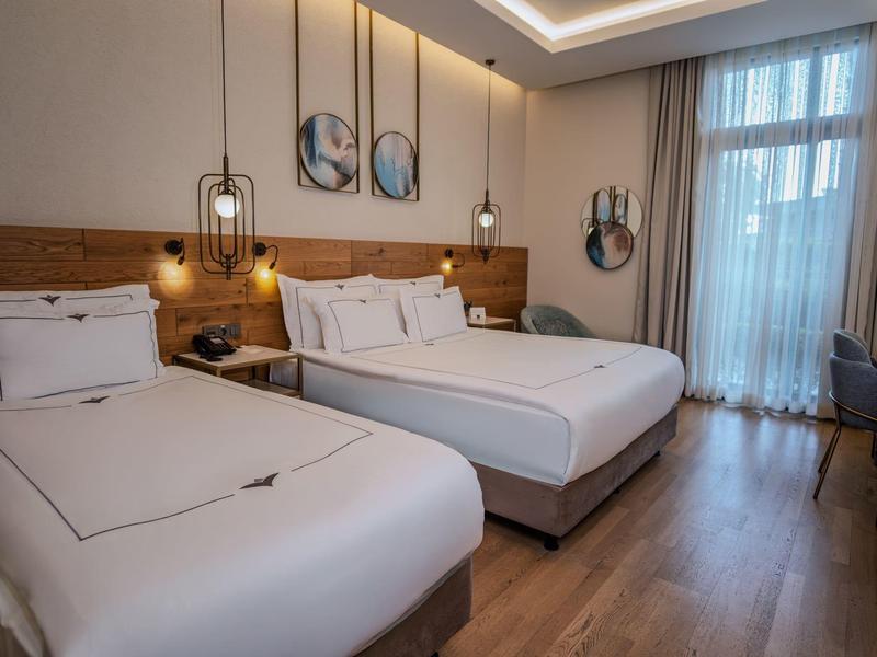 Camera d'hotel moderna con due grandi letti, pavimento in legno e illuminazione elegante