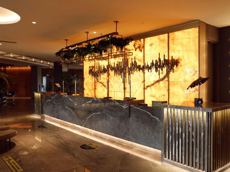 Reception elegante nella hall dell'hotel con banco in marmo illuminato e parete decorativa