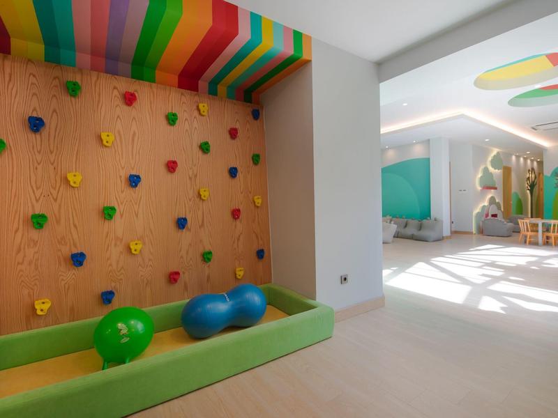 Sala giochi per bambini luminosa con parete da arrampicata e piscina di palline colorata