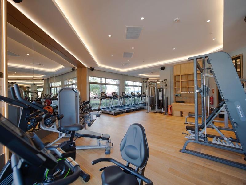 Palestra luminosa con attrezzature moderne e pavimento in legno in un hotel.
