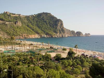 Beach with many umbrellas and mountain in the background along the coast.