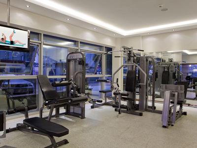 Modern gym with equipment and large windows in a hotel.