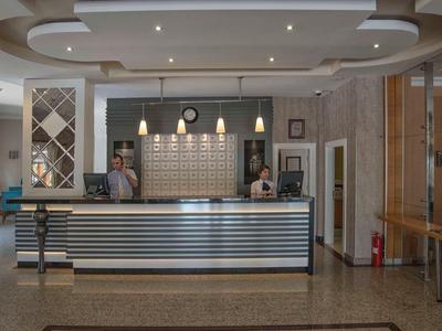 Hotel reception with modern front desk and two receptionists in the background.