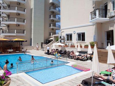 Hotel pool area with multiple pools, guests on sun loungers, and people relaxing in the water.
