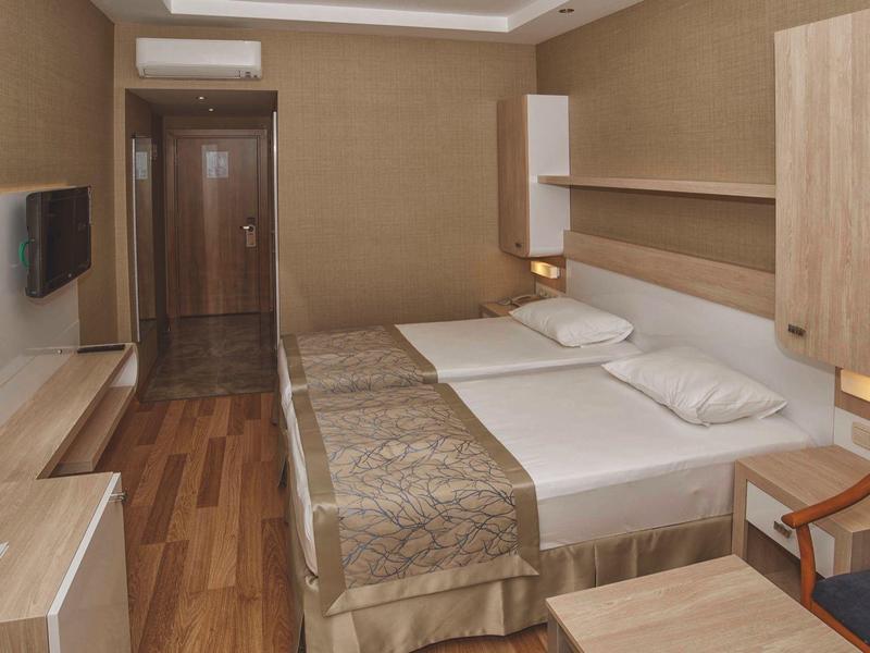 Modern hotel room with two beds, wooden furniture, and a flat-screen TV.