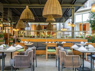 Ristorante d'hotel moderno con sedie elegante, grandi lampade e tavoli apparecchiati.