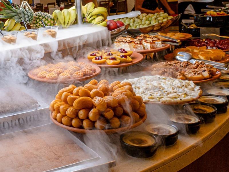 Buffet con una varietà di piatti dolci e salati e frutta, disposti in modo decorativo.