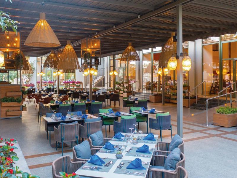 Ristorante moderno in hotel con tavoli apparecchiati e lampade eleganti in uno spazio interno aperto.