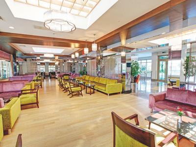Spacious hotel lobby with colorful seating, wooden flooring, and large windows letting in natural light.