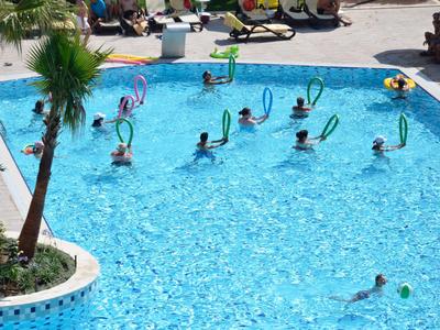 Niños jugando con aros coloridos en la piscina exterior de un hotel en un día soleado.