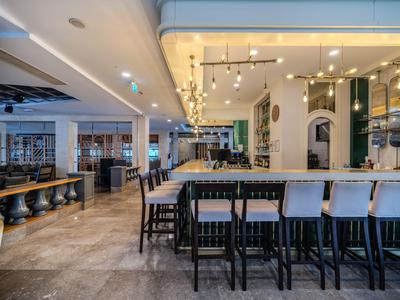 Moderní hotelový bar s vysokými stoličkami a stylovým osvětlením.
