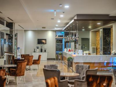 Moderní hotelová lounge s pohodlnými křesly, stoly a osvětleným barem.
