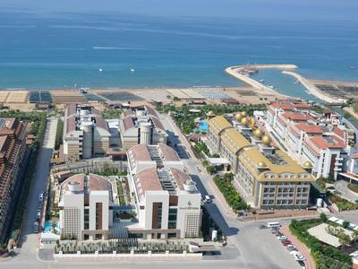 Aerial view of a coastal resort with hotels, sandy beach, and blue ocean under clear sky.