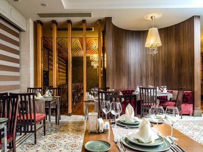 Elegantní restaurace s dřevěnými stěnami, prostřenými stoly a pohodlnými židlemi.