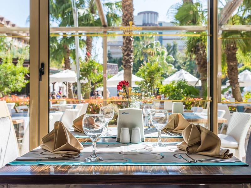 Outdoor restaurant table with napkins, glassware, and palm trees in the background on a sunny day
