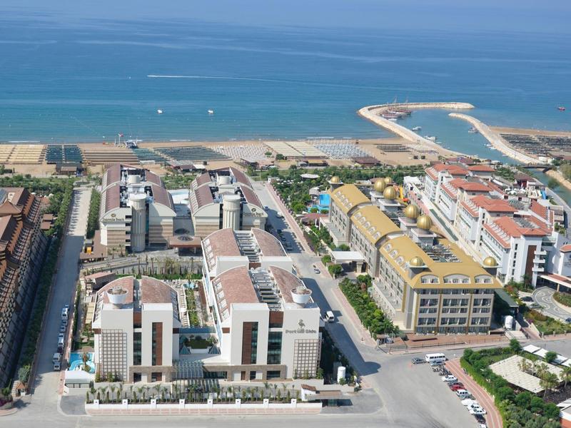 Aerial view of a coastal resort with hotels, sandy beach, and blue ocean under clear sky.