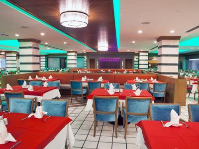 Grand restaurant avec nappes rouges, chaises bleues et design moderne.