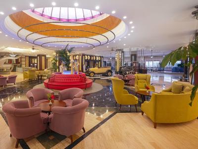 Hotel-Lobby mit bunten Sitzgruppen, moderner Beleuchtung und großem, dekorativem Deckenlicht.