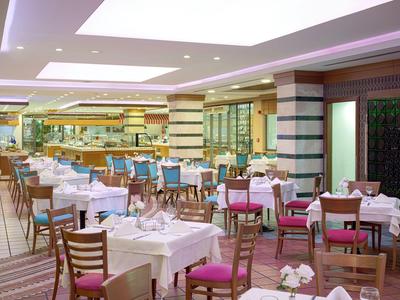 Modernes Restaurant mit gedeckten Tischen und farbigen Stühlen in einem hellen Innenraum.
