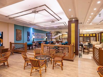 Gemütlicher Hotel-Loungebereich mit Holzmöbeln, Teppichboden und moderner Beleuchtung.