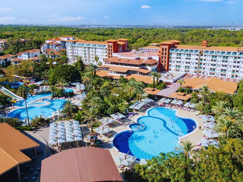 Duży hotelowy ośrodek z wieloma basenami i zielonym otoczeniem pod niebieskim niebem.