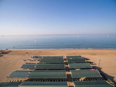 Vista di una spiaggia di sabbia tranquilla con diverse file di lettini verdi affacciati sul mare