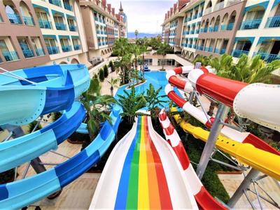 Hotel water park with colorful slides and outdoor pool between two buildings.