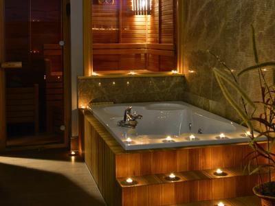 Cozy spa area with a wooden hot tub surrounded by candles and warm lighting.