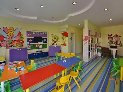 Colorful children's playroom with small tables, chairs, toys, and bright wall art.
