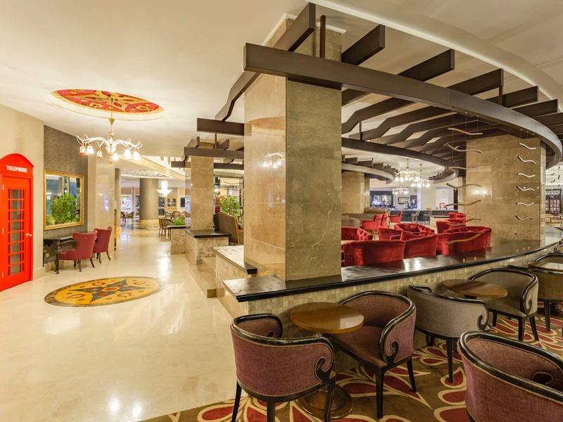 Spacious hotel lobby with elegant seating and classic red phone booths near the entrance.