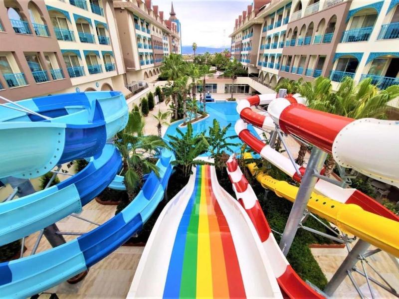 Hotel water park with colorful slides and outdoor pool between two buildings.