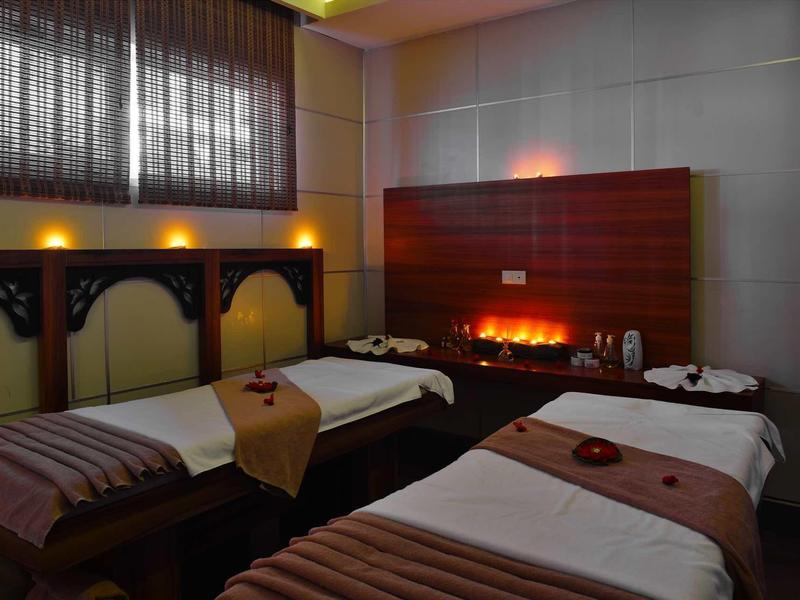 Cozy spa room with two massage beds, soft lighting, and a warm electric fireplace.