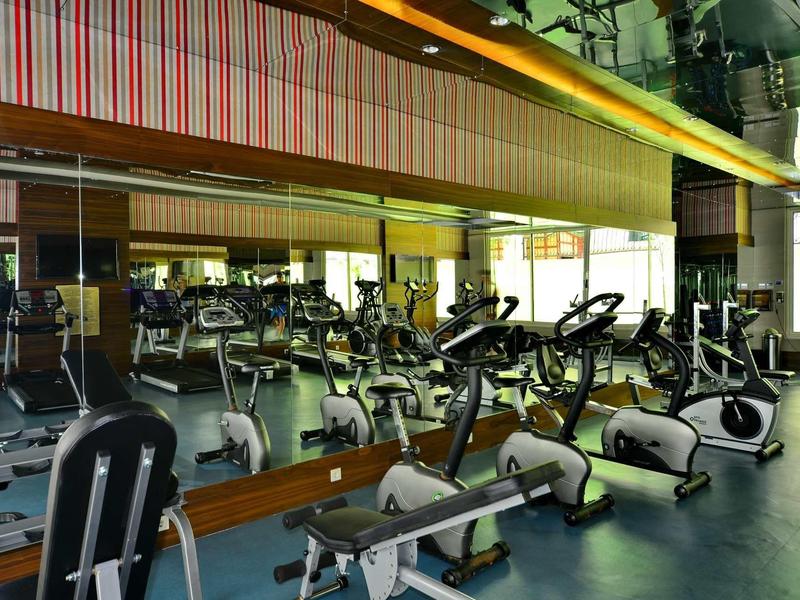 Modern gym with rowing machines and exercise bikes along mirrored wall.