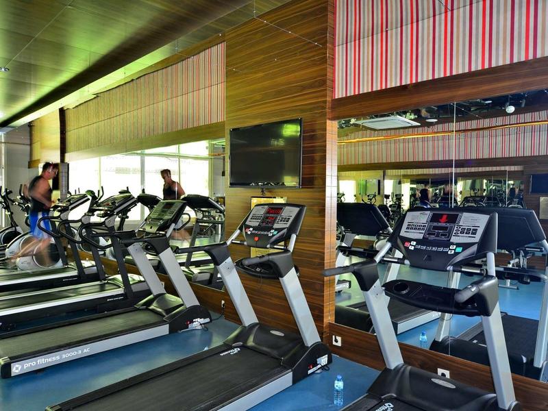 Modern gym with treadmills facing large mirrors in a hotel fitness center.