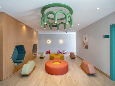 Moderne Hotellobby mit bunten Sitzgelegenheiten und einzigartiger grüner Deckenleuchte.