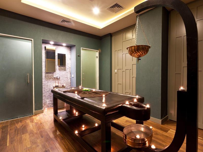 Camera spa tranquilla con lettino da massaggio in legno e luce calda.