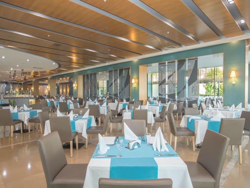 Ampia sala da pranzo con tavoli eleganti apparecchiati con tovaglie azzurre e bianche.