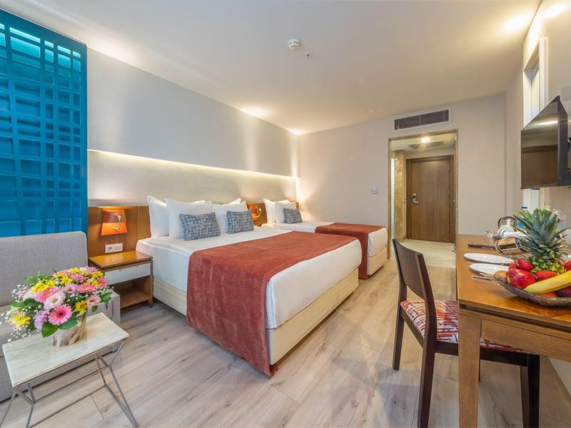 Camera d'hotel moderna con letto matrimoniale, scrivania, sedia e decorazioni eleganti.