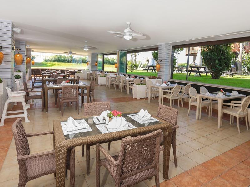 Sala da pranzo dell'hotel luminosa con tavoli apparecchiati e vista sul giardino.