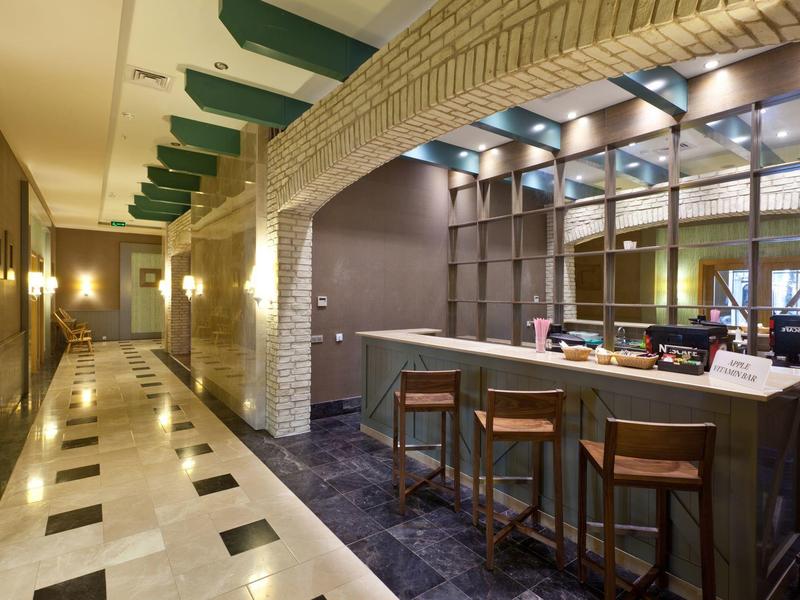 Corridoio d'hotel moderno con bar illuminato e sgabelli alti.