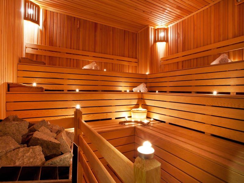 Interno accogliente di una sauna in legno con luci soffuse e pietre calde.