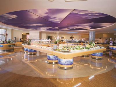 Großer moderner Speisesaal mit zentralem Buffet und farbigem Wolkenbild an der Decke.