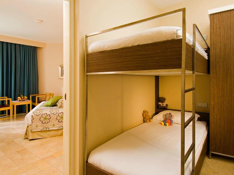 Schlafzimmer mit Etagenbett, Einzelbett, Schrank und Sitzbereich mit Tisch und Stühlen.