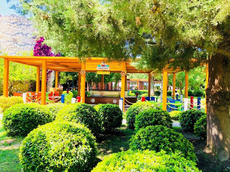 Bunte, überdachte Sitzplätze im Garten, umgeben von grünen Büschen und Bäumen.