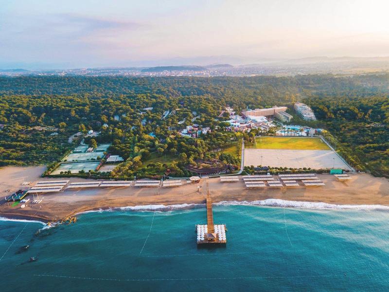 Blick auf eine Küstenstadt mit langen Stränden, einem Pier im Meer und viel Grünland im Hintergrund.