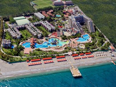 Aerial view of a large beach resort with multiple pools, buildings, and a pier extending into the sea.